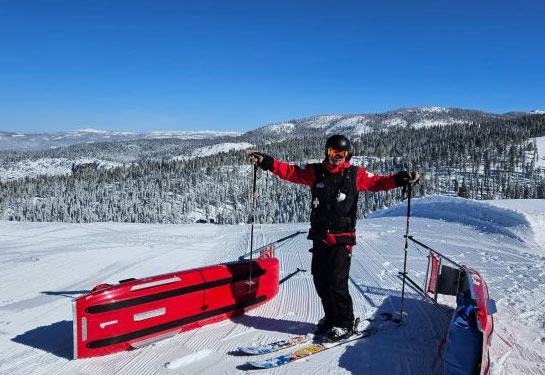 Back of man in red ski attire pulling tobaggan.